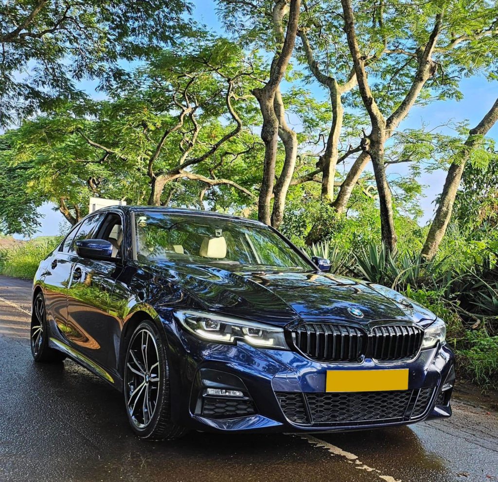 BMW 330i sedan parked on a scenic coastal road in Mauritius, with the Liberta Car Rental .