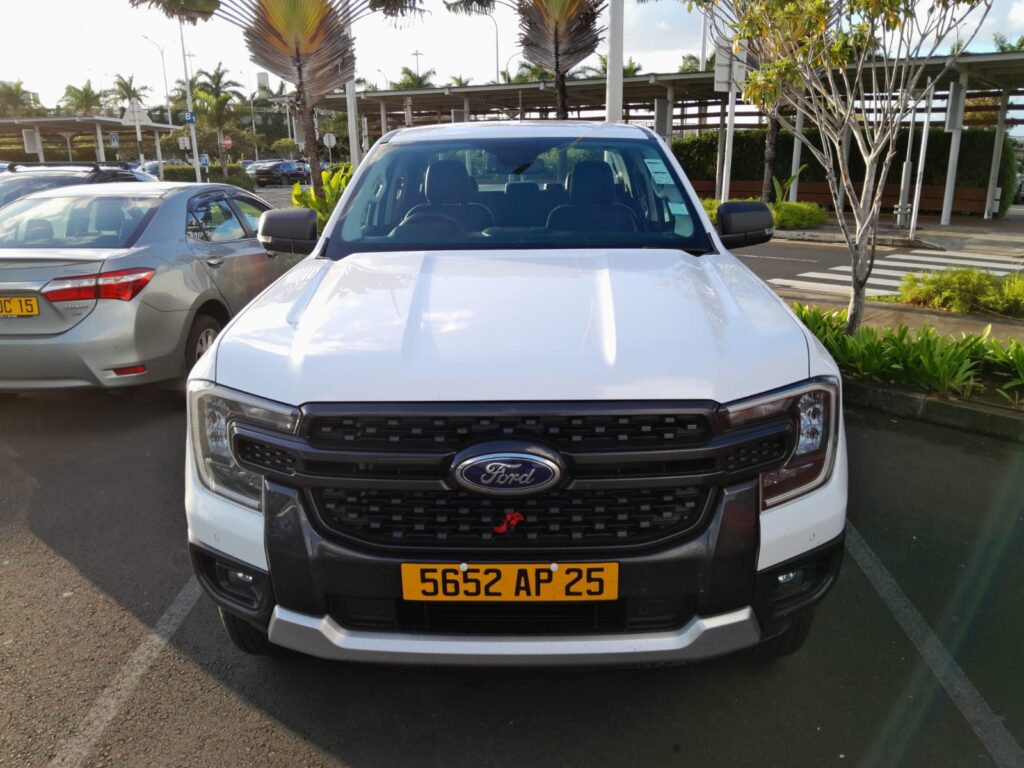Ford Ranger 2.0 XLT 4×4 pickup for rent in Mauritius from Liberta Car Rental—silver double-cab parked on a sandy track overlooking the Indian Ocean and palm-fringed coastline.