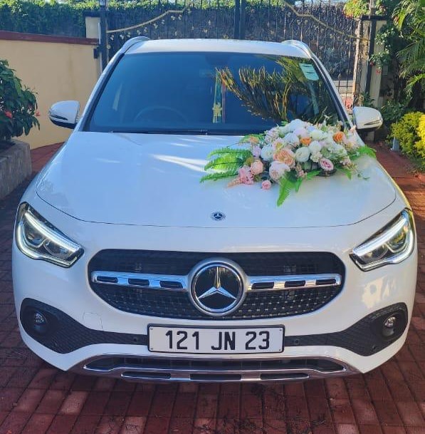 Mercedes GLA180 luxury SUV for rent in Mauritius from Liberta Car Rental—sleek midnight-blue vehicle parked beside an upscale beach resort at sunset, palm trees and the Indian Ocean in the background.