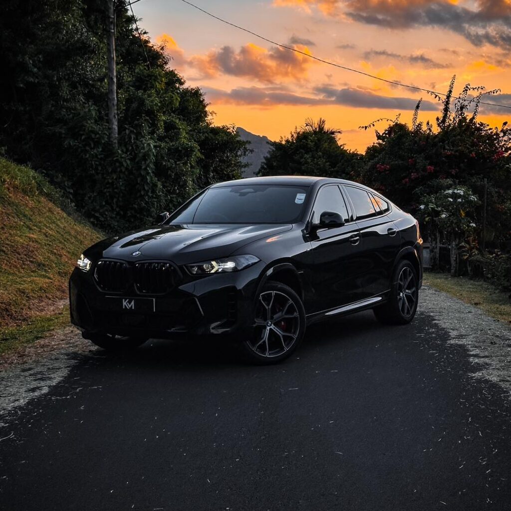 Luxury car rental in Mauritius – BMW X6parked near a beach resort with palm trees and ocean view. Luxurious 2025 BMW X6 available for high-end car rental in Mauritius through Liberta Car Rental."