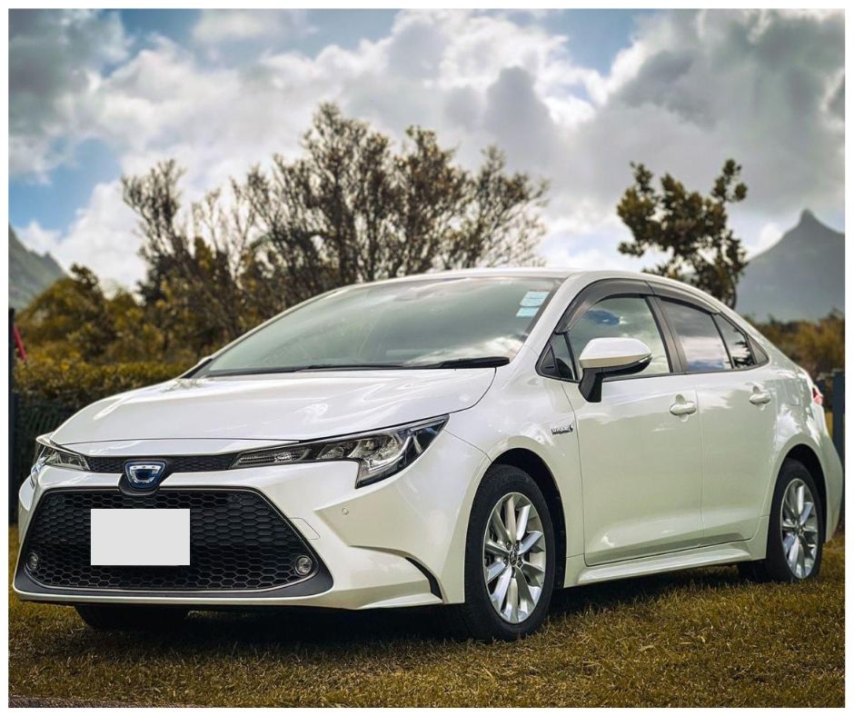 Toyota Corolla Sedan for rent in Mauritius from Liberta Car Rental—sleek silver sedan parked on a coastal road with turquoise lagoon and palm trees in the background.