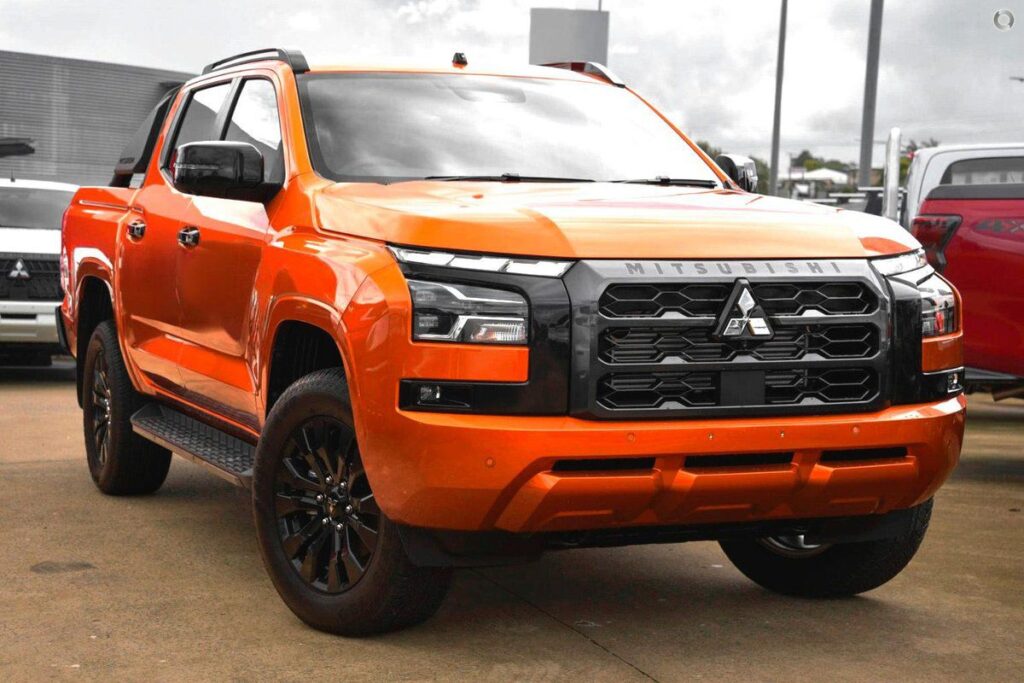 Mitsubishi Triton 4×4 Turbo Diesel available for car rental services in Mauritius from Liberta Car Rental—rugged white pickup parked on a coastal track with mountains and lagoon in the background.