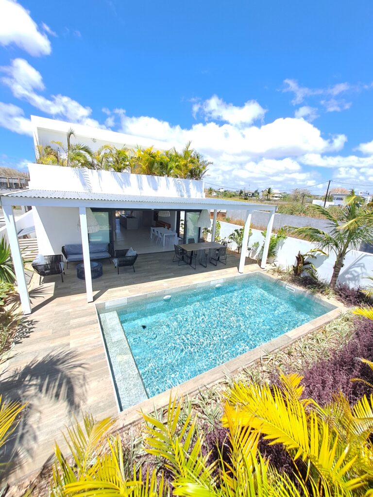 Modern luxury villa in Grand Baie featuring a saltwater pool, lush tropical garden, and panoramic ocean views